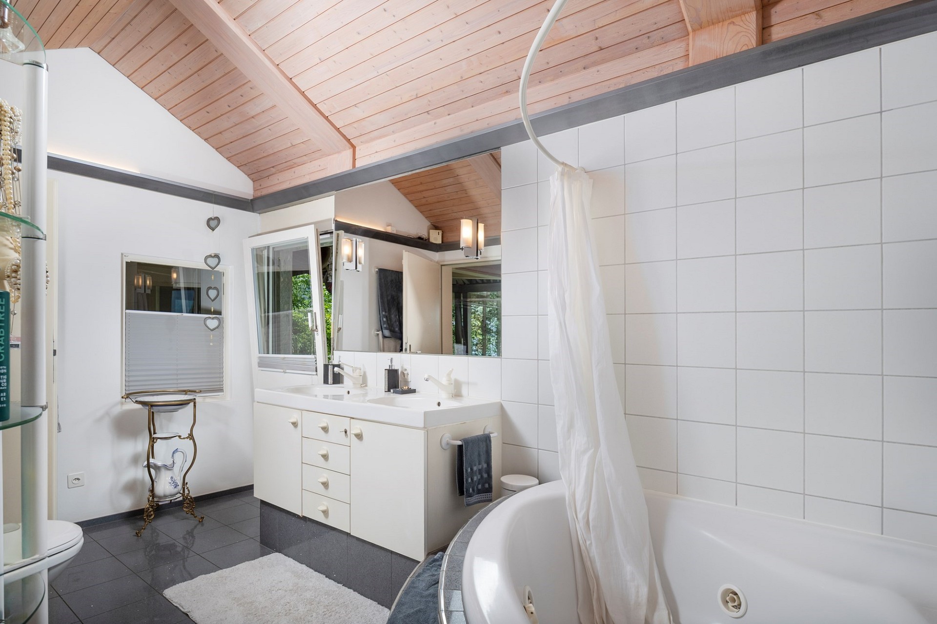 Helles Badezimmer mit Holzdecke und freistehender Wanne