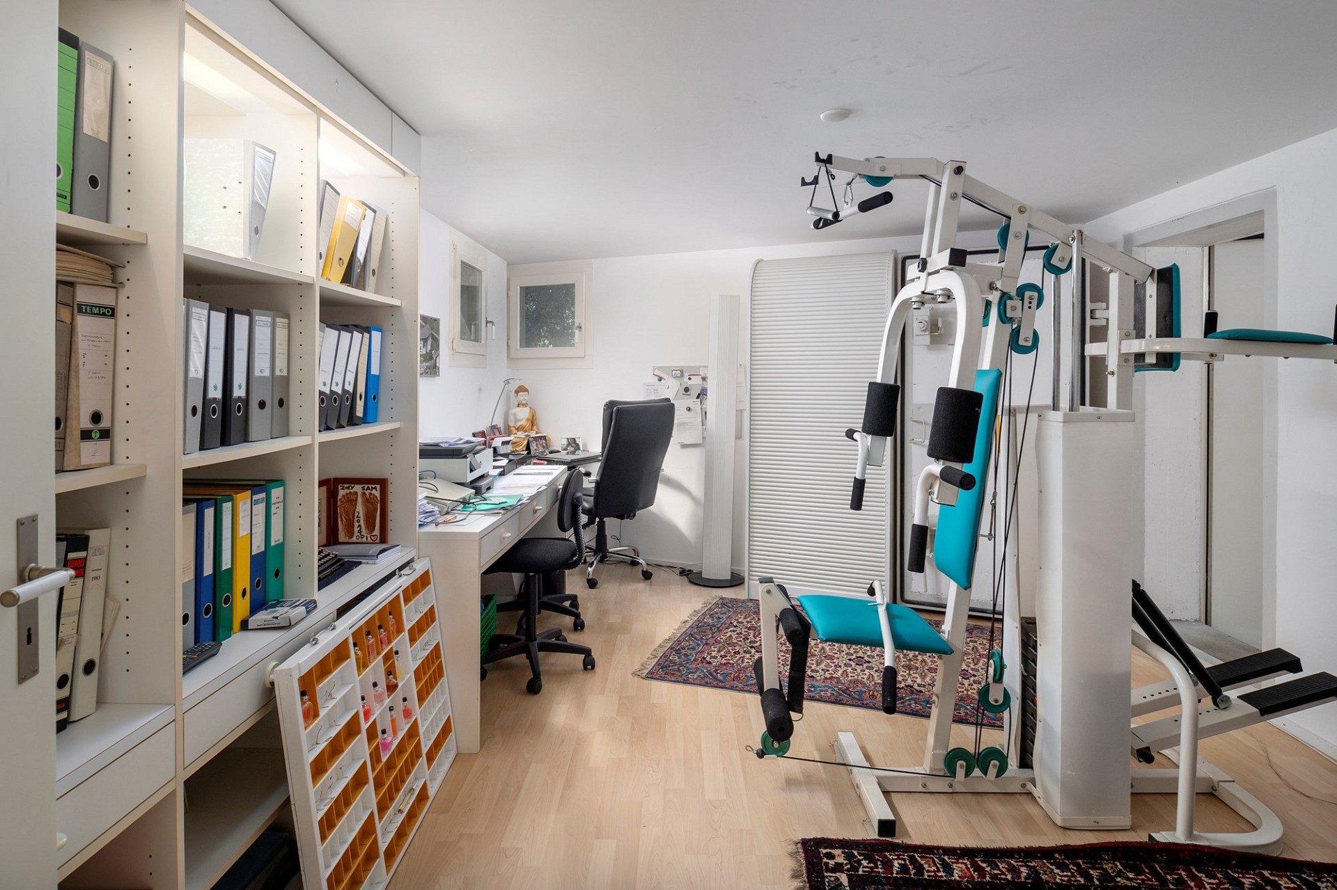 Heller Multifunktionsraum mit Trainingsgeräten und Bürobereich