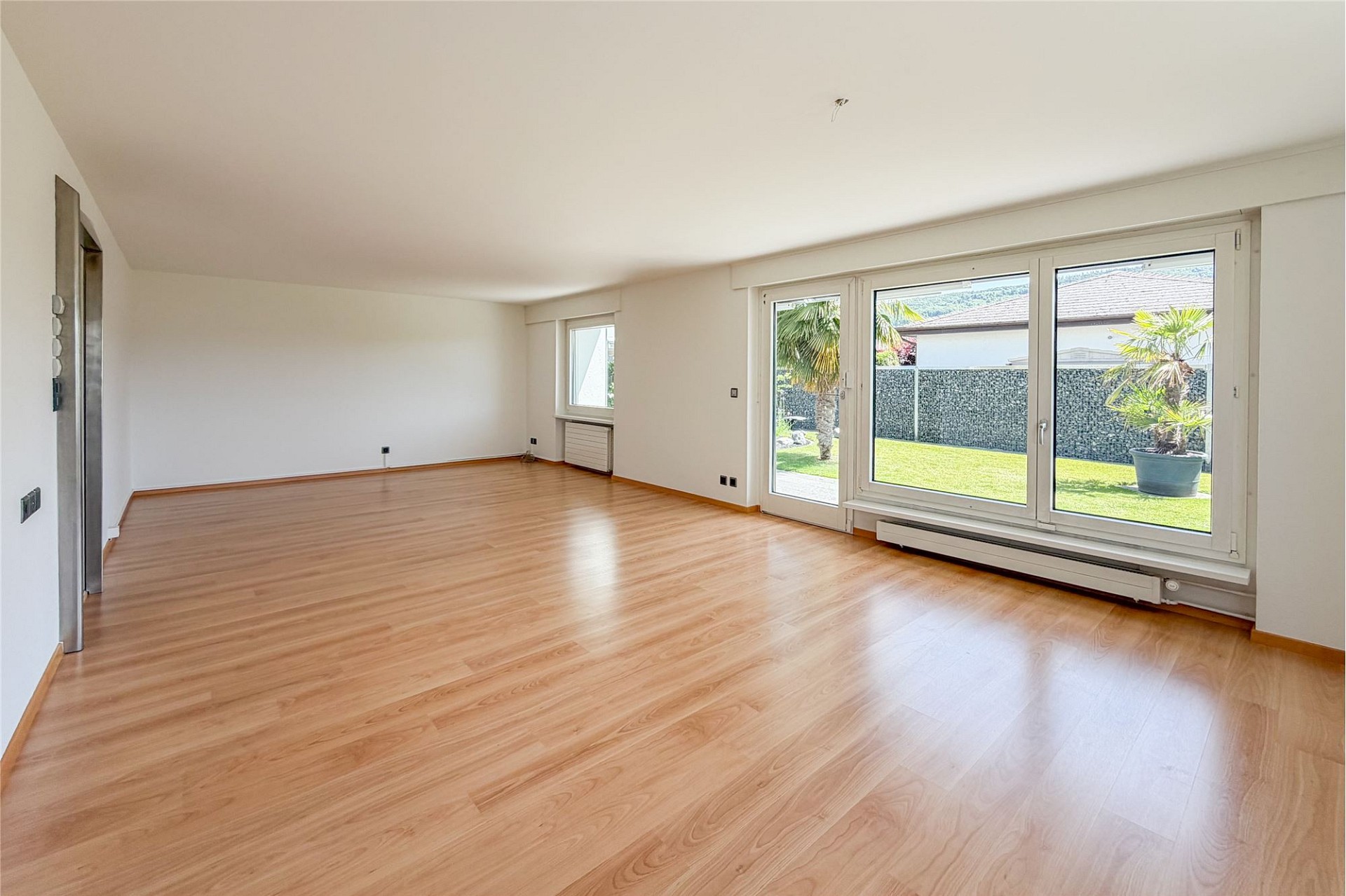 Großer leerer Wohnraum mit Blick in den Garten