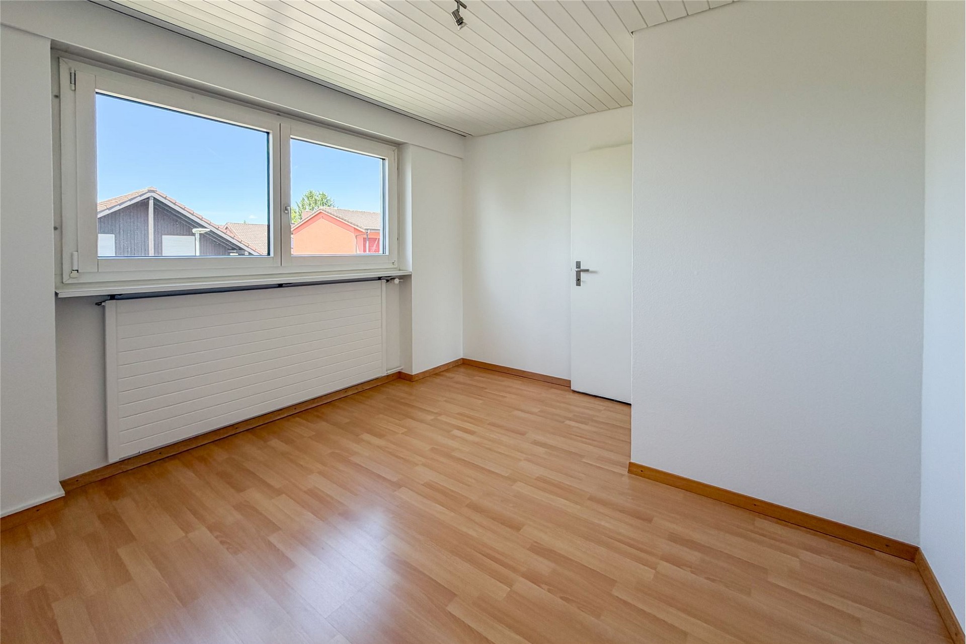 Helles leeres Zimmer mit Fenster und Holzboden
