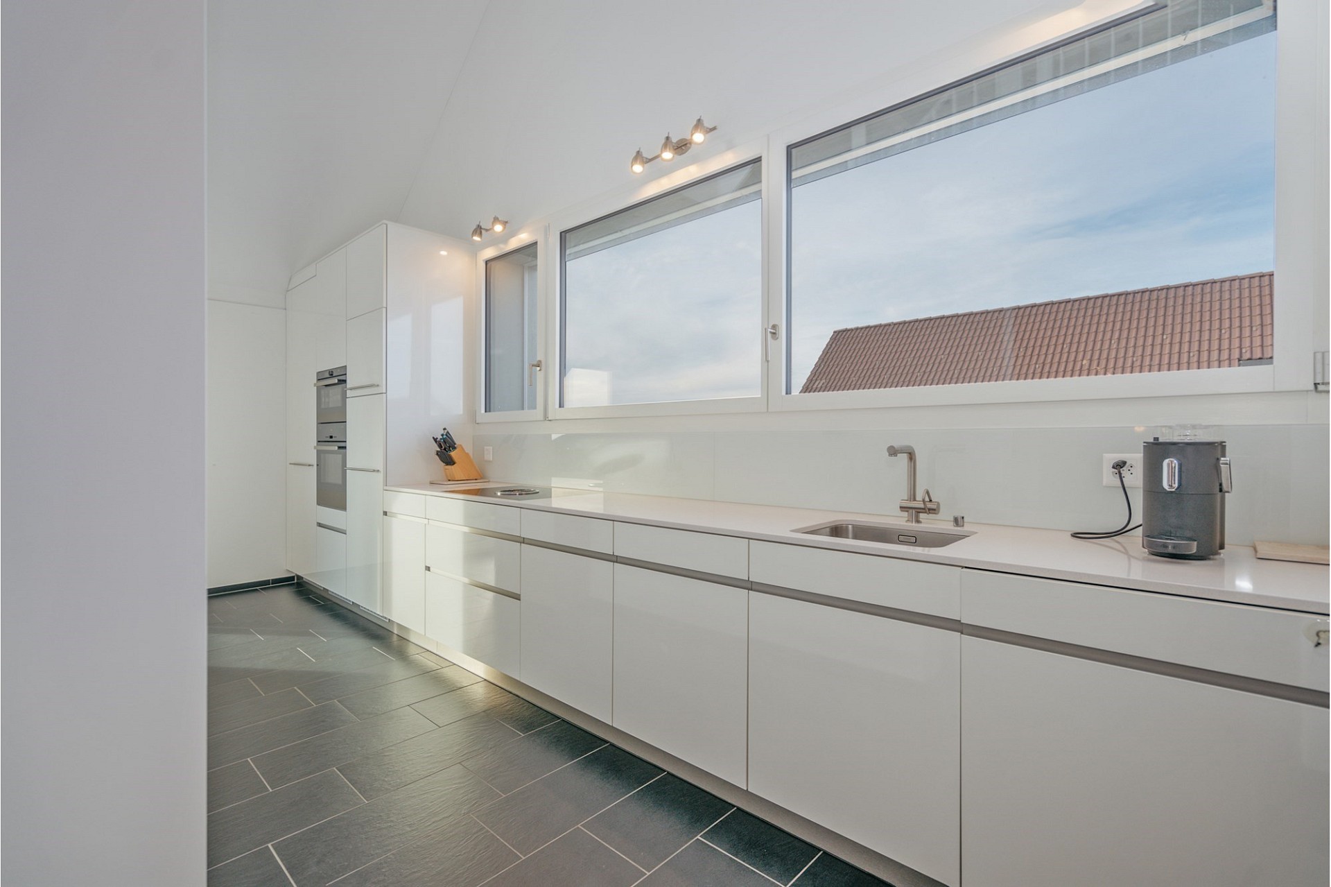 Moderne weiße Küche mit großen Dachfenstern