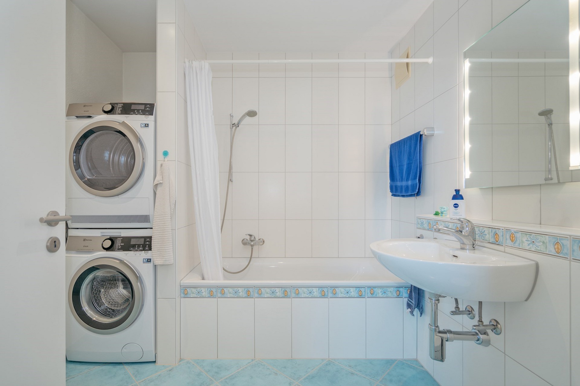 Badezimmer mit Waschmaschinen-Turm und Badewanne