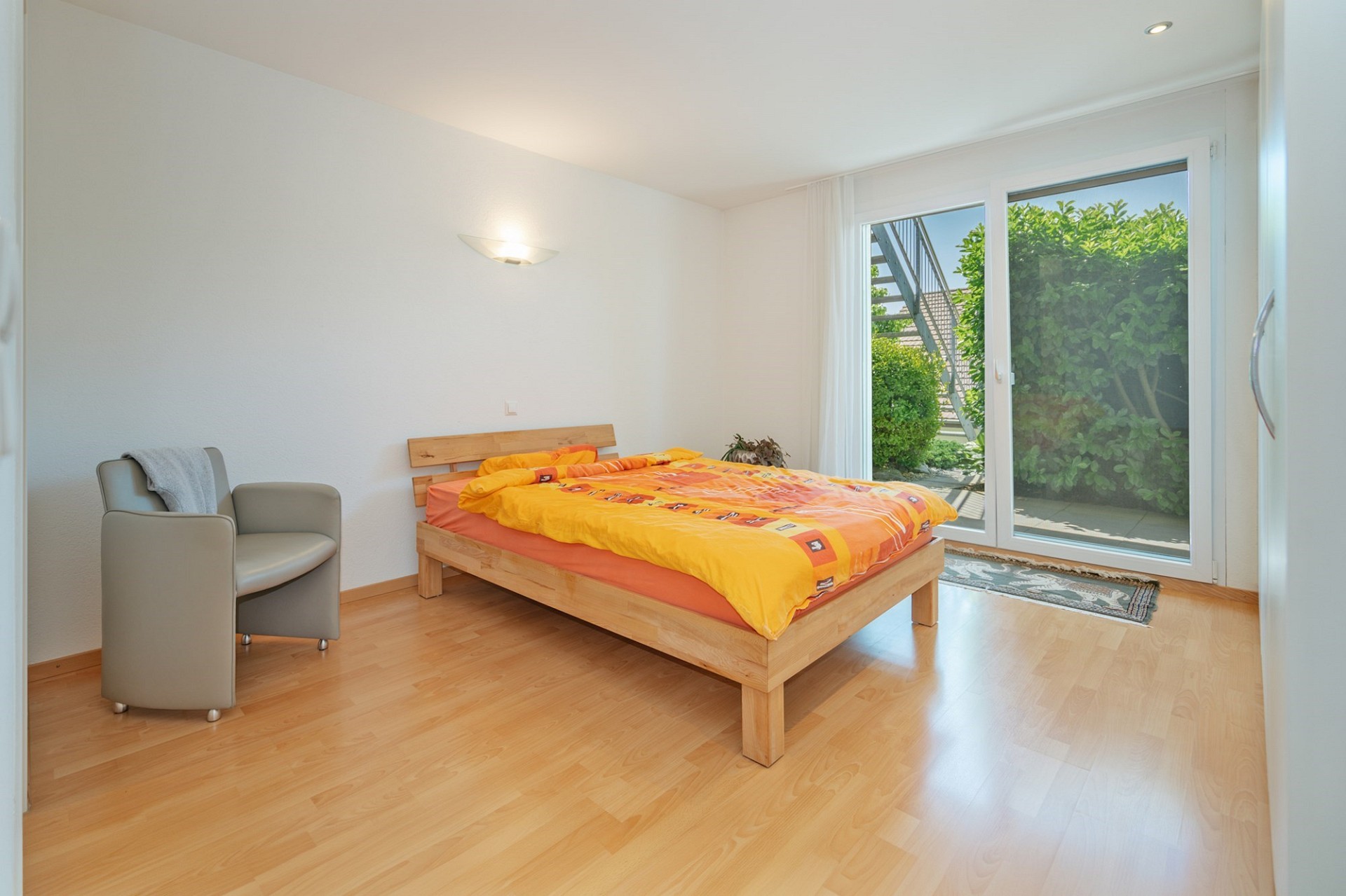 Helles Schlafzimmer mit Holzbett und Terrassentür