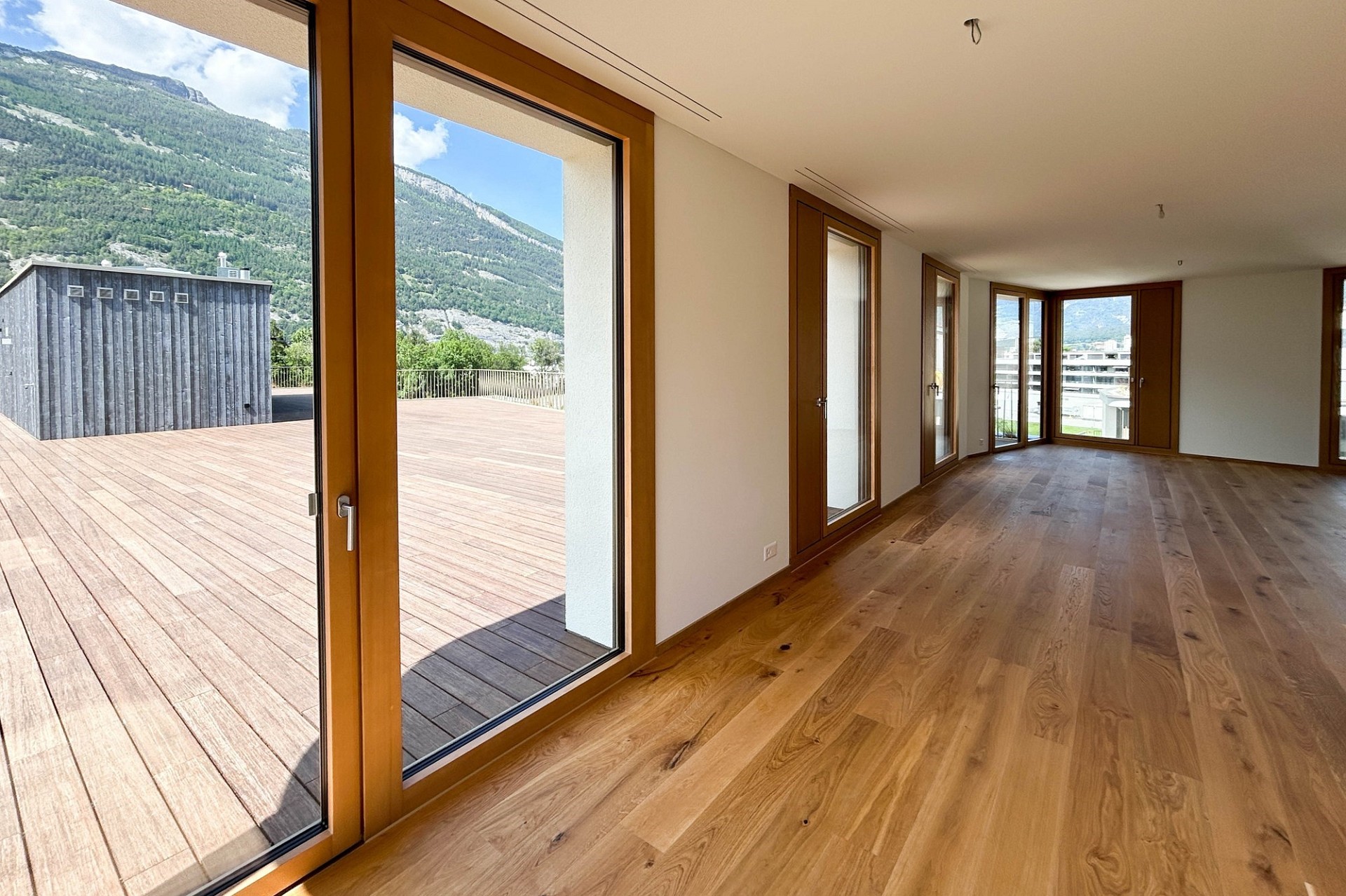 Heller Wohnraum mit großflächigen Fensterfronten und Bergblick