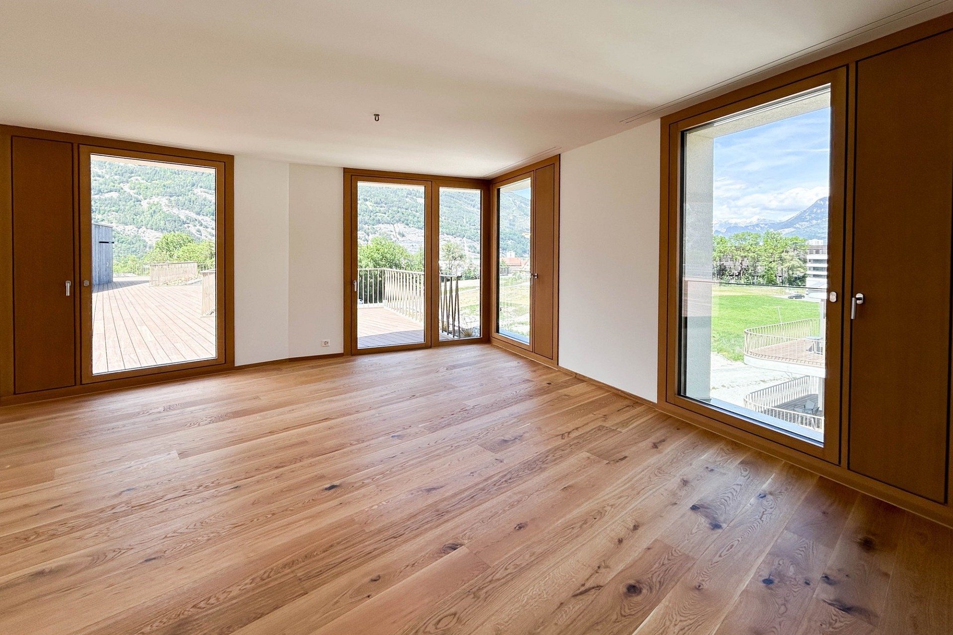 Heller leerer Wohnraum mit Panoramafenstern und Bergblick