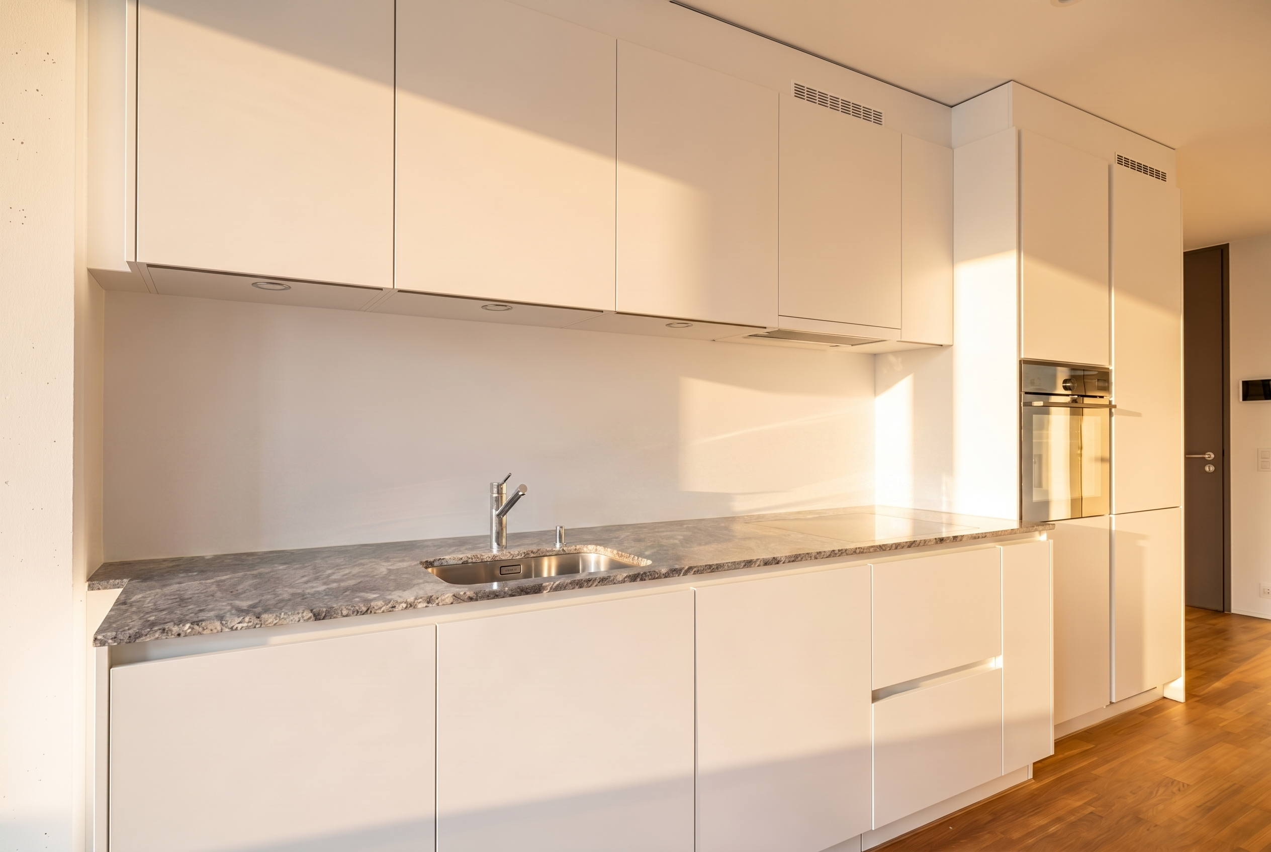 Moderne weiße Küche mit Naturstein-Arbeitsplatte