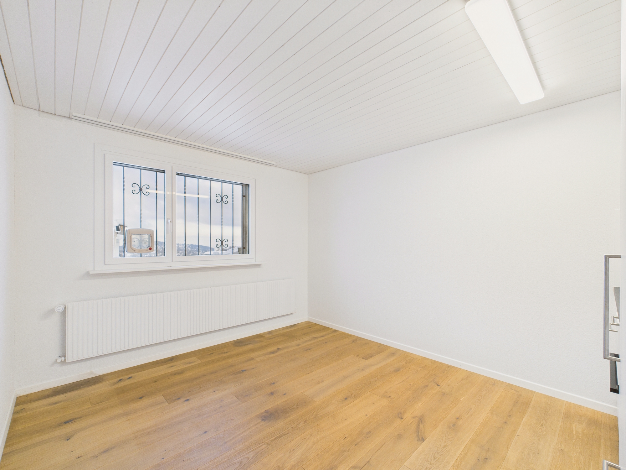 Heller leerer Raum mit Holzparkett und Fenster