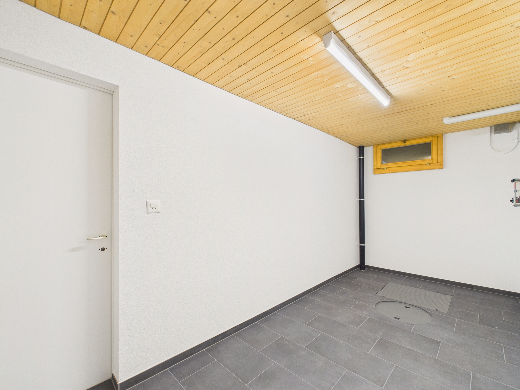Heller Hauswirtschafts- bzw. Technikraum mit Fliesenboden und Holzdecke