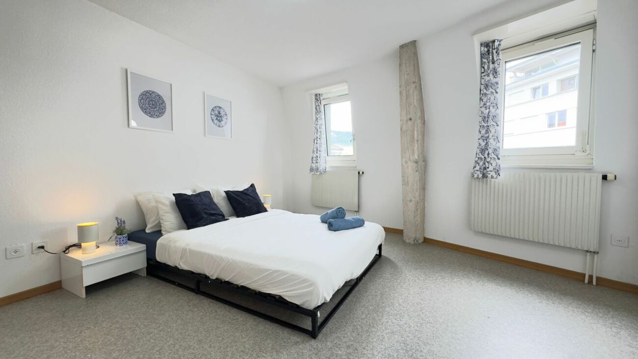 Helles Schlafzimmer mit zwei Fenstern und Doppelbett