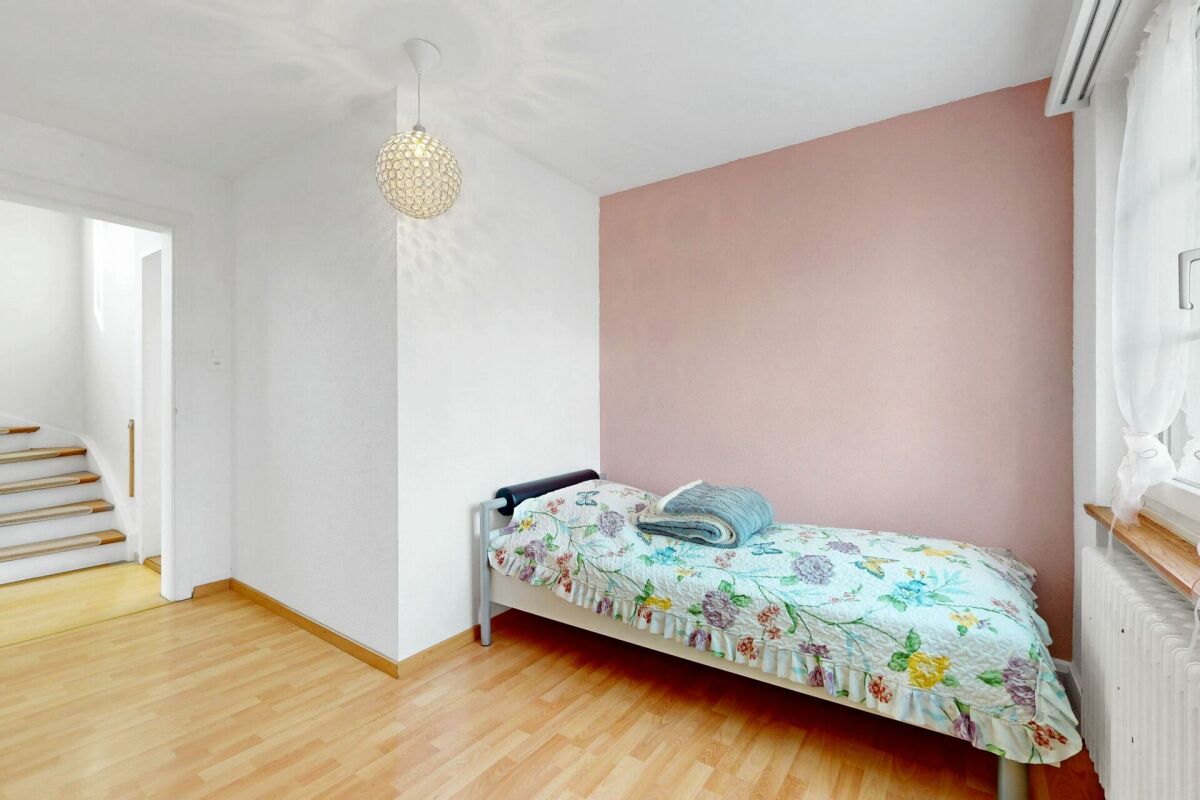 Helles Schlafzimmer mit Einzelbett und Treppenblick