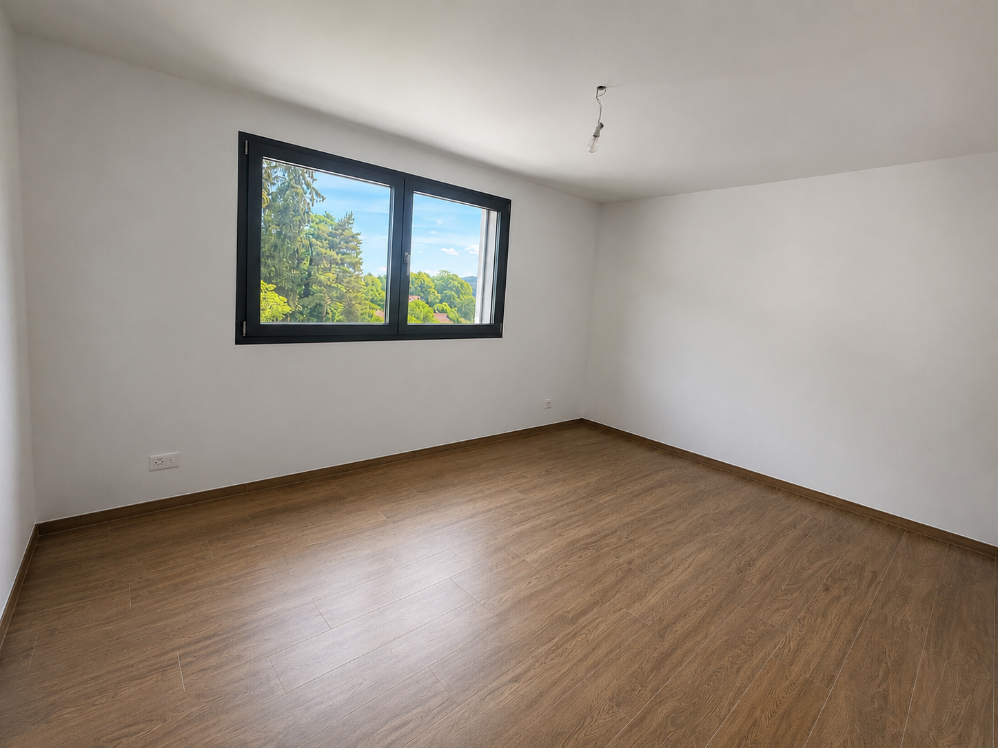 Leeres Zimmer mit Holzoptik-Boden und Fenster