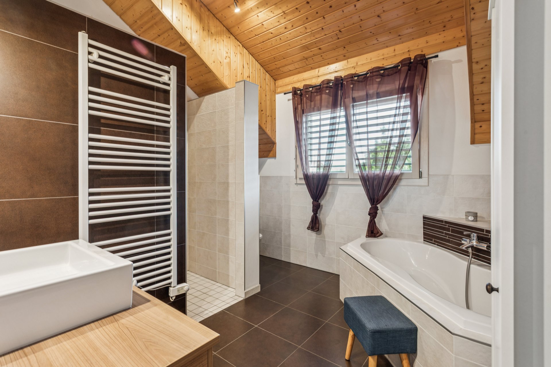 Helles Badezimmer mit Holzdecke und Badewanne