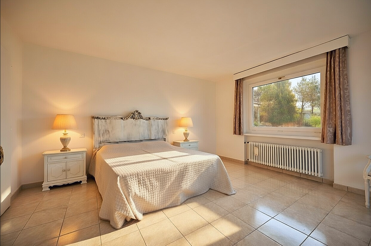 Helles Schlafzimmer mit klassischem Bett und großem Fenster