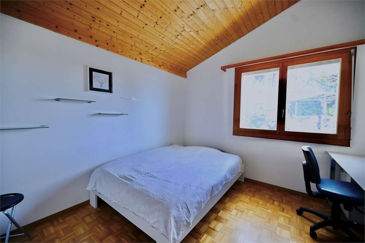 Helles Schlafzimmer mit Holzdecke und Schreibtisch