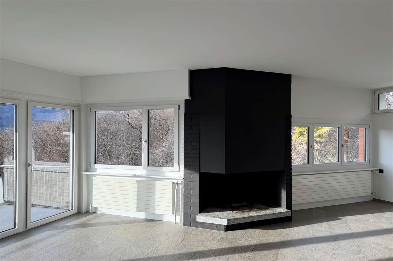 Wohnraum mit Kamin und großen Fenstern
