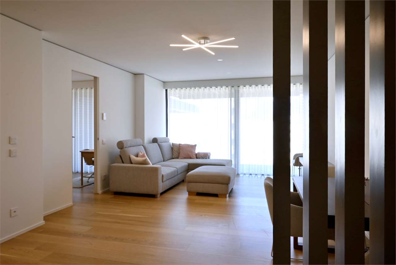 Heller, moderner Wohnraum mit Sofa und großer Fensterfront