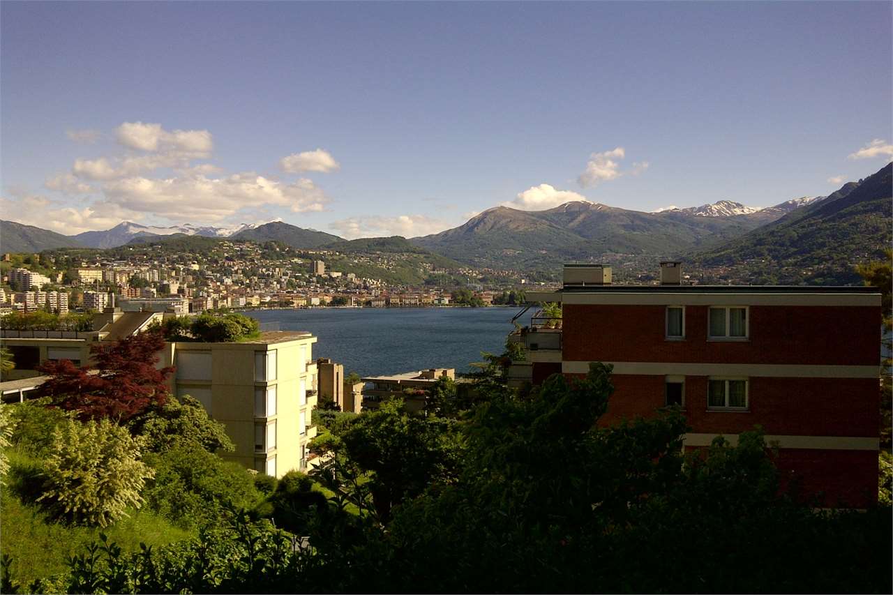 Seeblick mit Bergkulisse und Wohnhäusern