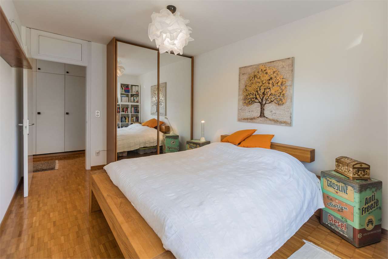 Helles Schlafzimmer mit Holzboden und Spiegelschrank