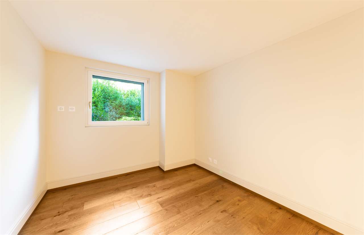 Leerer, heller Raum mit Holzfußboden und Fenster zum Grün