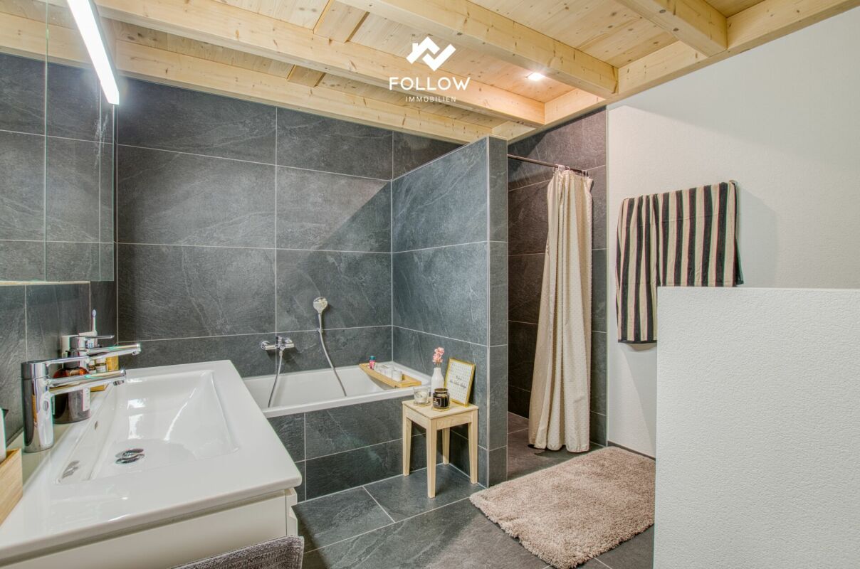 Modernes Badezimmer mit Holzdecke und dunkler Natursteinoptik