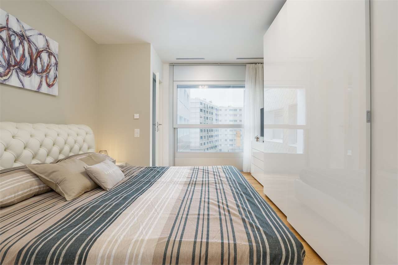 Helles Schlafzimmer mit großer Fensterfront und weißem Kleiderschrank