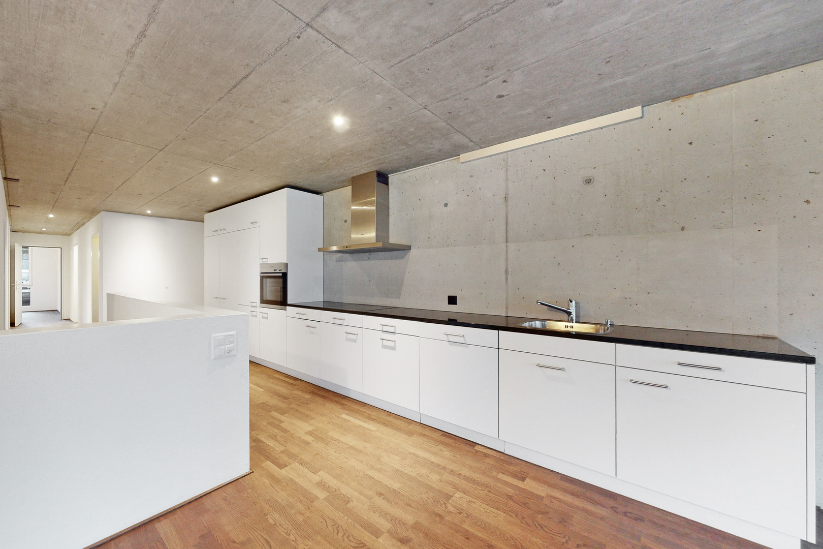Offene moderne Küche mit Sichtbeton und Holzboden