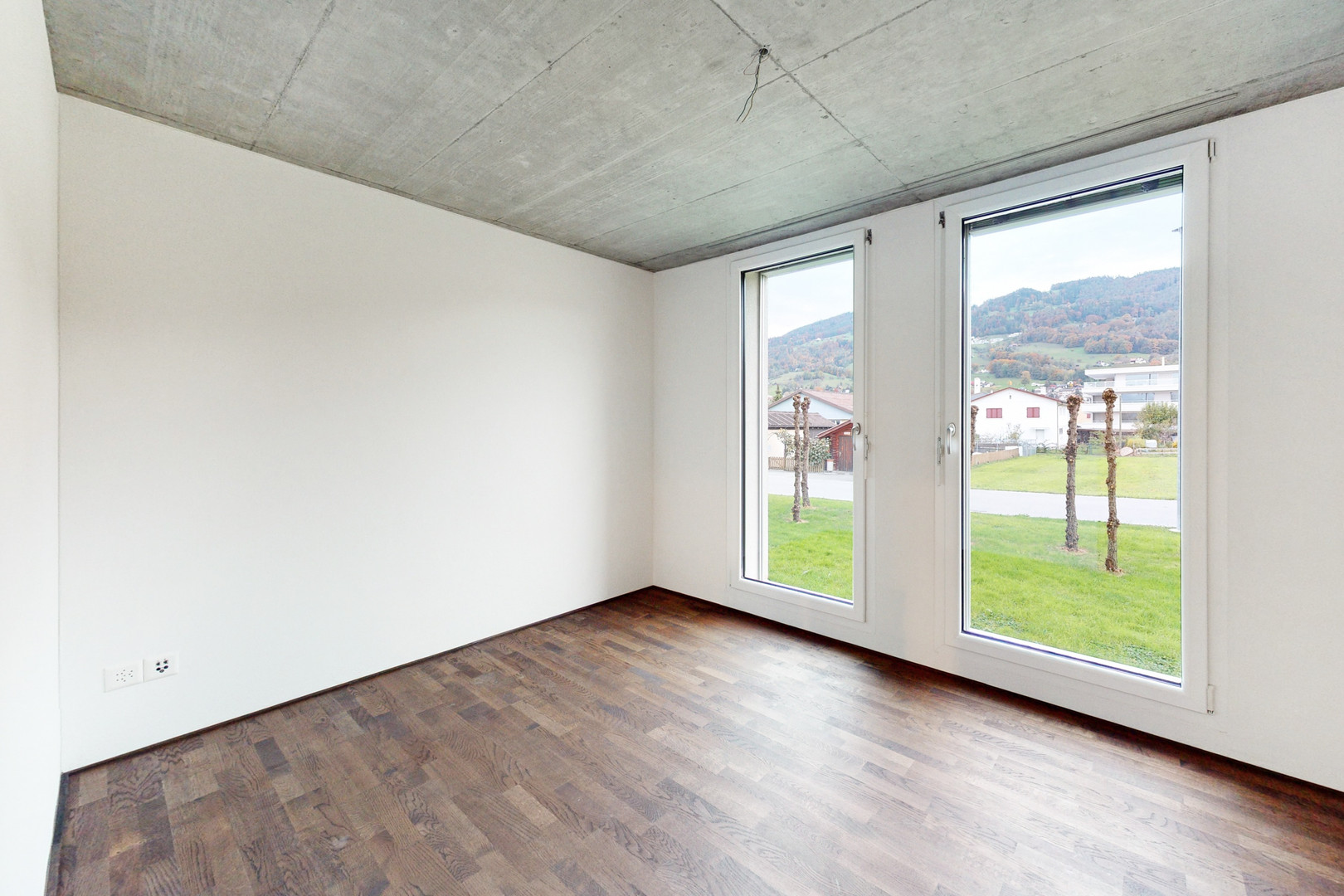 Leerer Raum mit zwei großen Fenstern und Blick ins Grüne