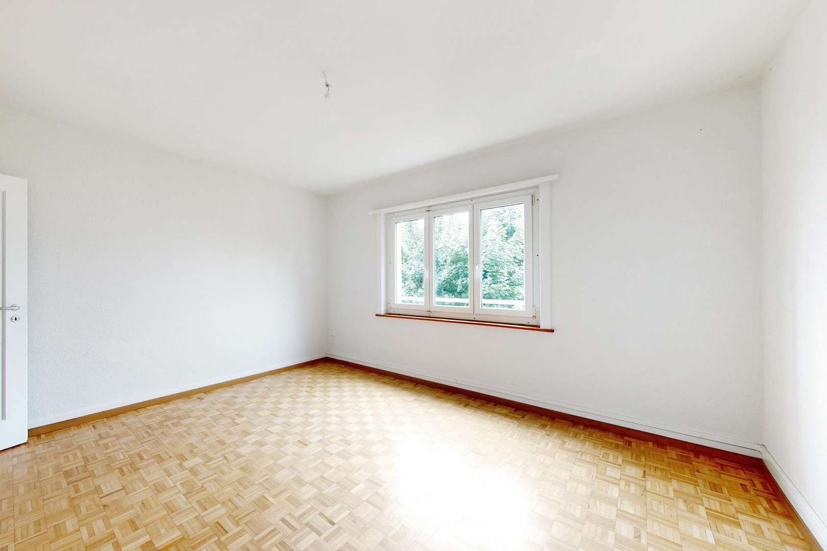 Heller leerer Raum mit Parkett und Fenster