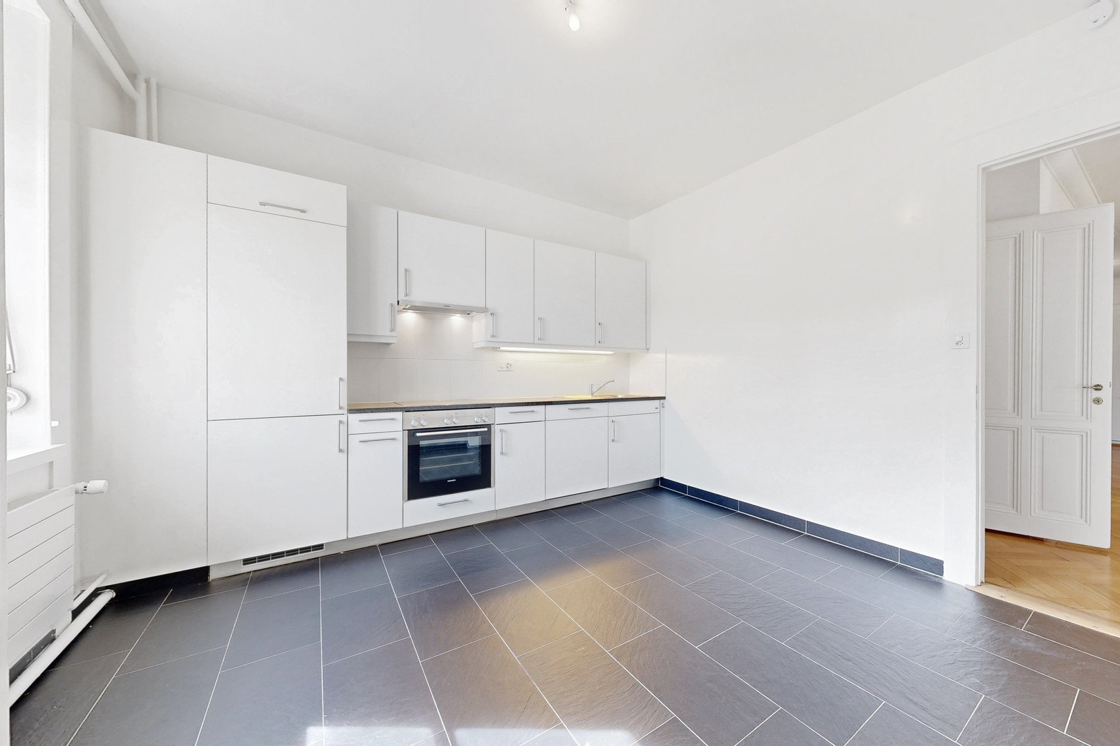 Helle, modernisierte Küche mit großformatigem Boden und weißen Fronten