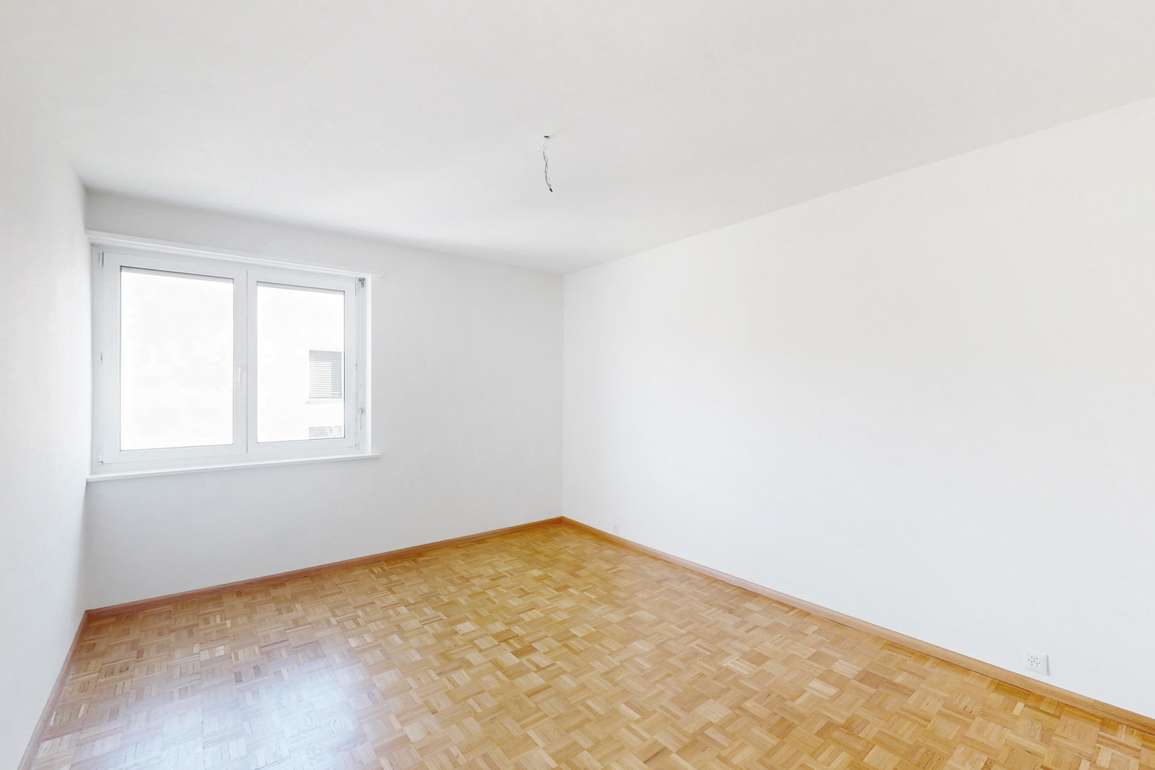 Heller leerer Raum mit Parkett und Fenster