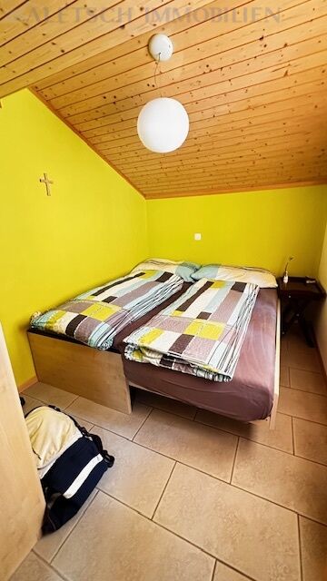 Kleines Schlafzimmer mit gelben Wänden und Holzdecke