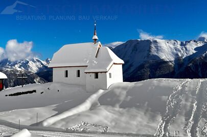 Schneebedeckte Bergkirche in alpiner Landschaft