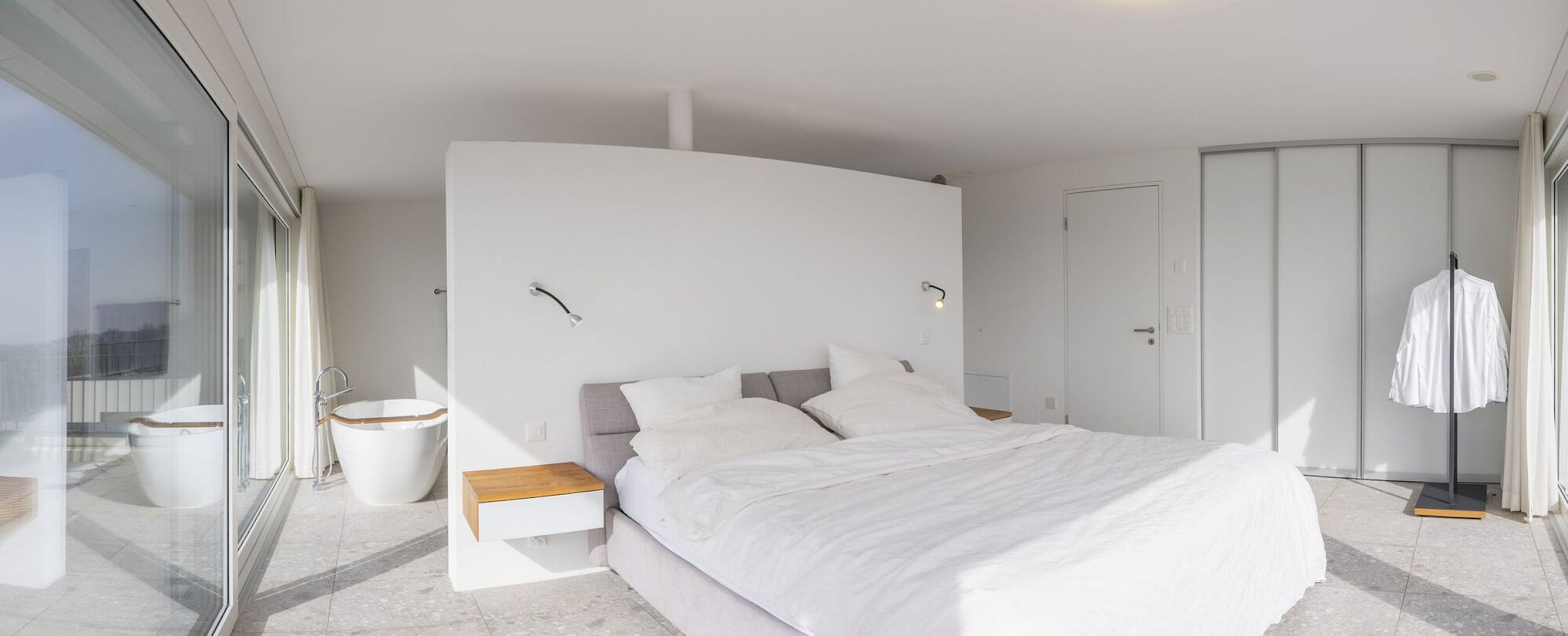 Helles Schlafzimmer mit offener Badzone und großflächigen Glasfronten