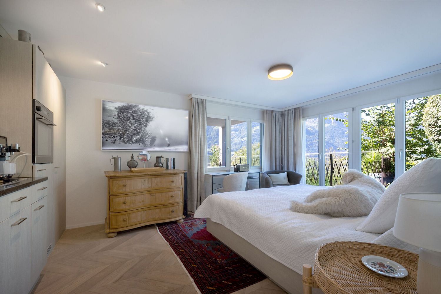 Helles Schlafzimmer mit Küchenzeile und Bergblick
