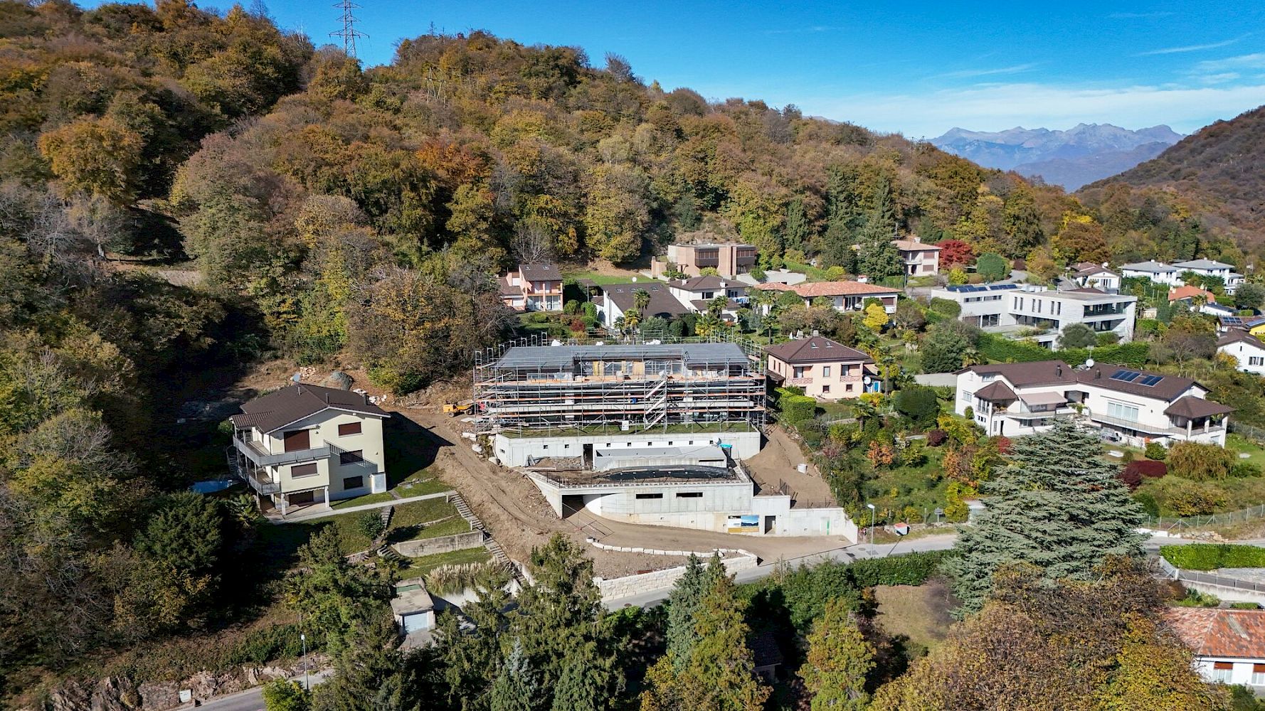 Luftaufnahme eines Wohngebiets am Berghang mit einer Baustelle im Zentrum