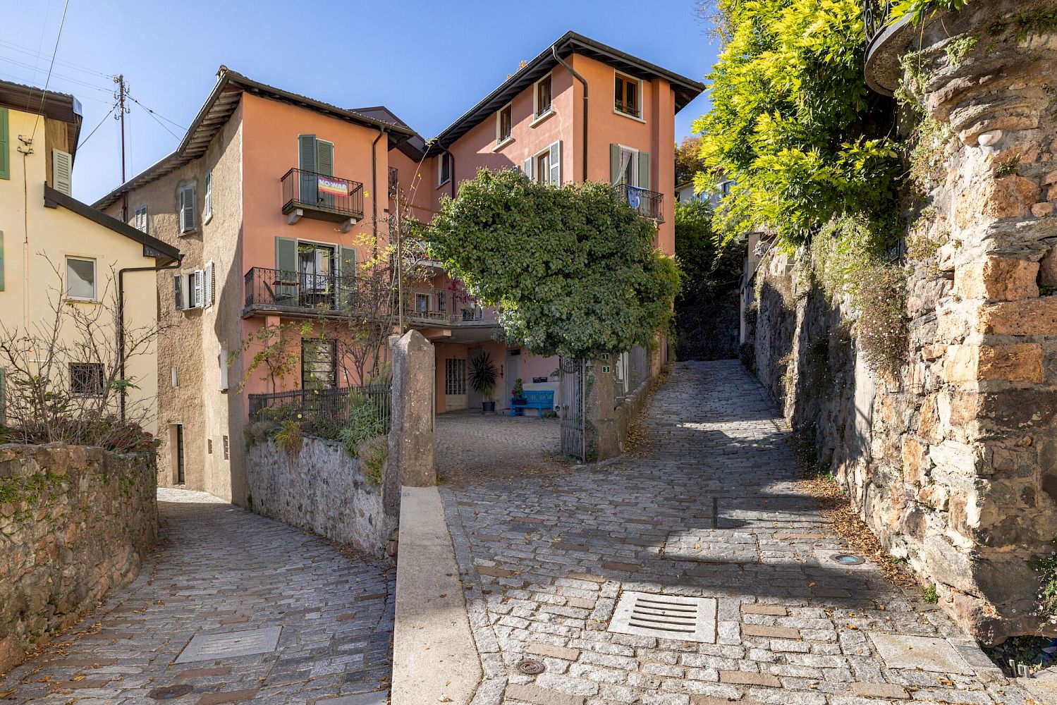 Enge Wohnstraße mit mediterranen Häusern und steiler Pflasterauffahrt