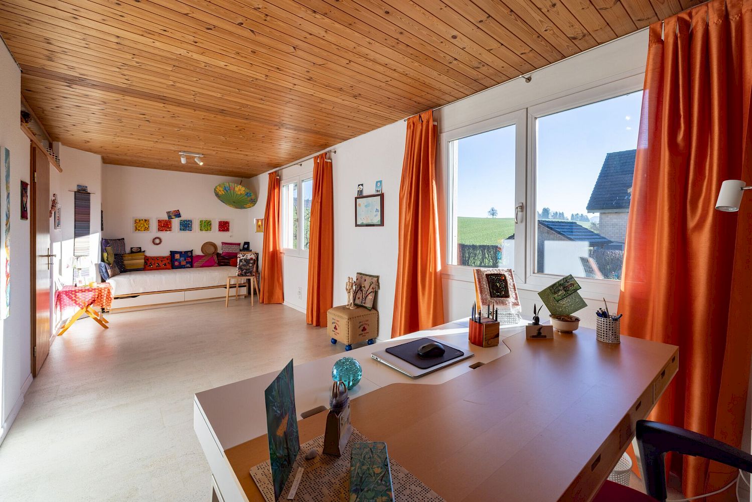 Heller Wohnraum mit Holzdecke und orangefarbenen Vorhängen