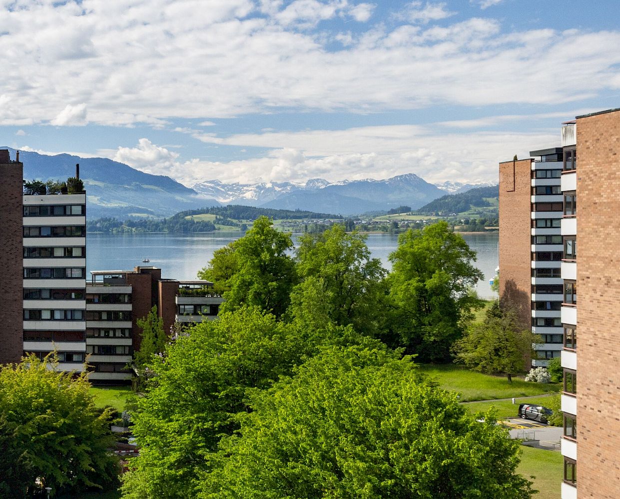 Blick auf See und Berge zwischen Wohngebäuden