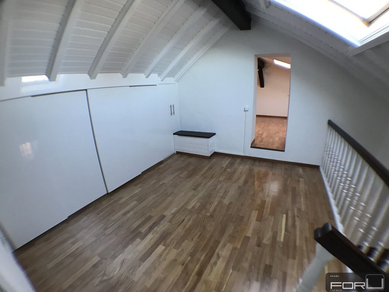 Dachgeschossraum mit Holzfußboden und weißen Schrägflächen
