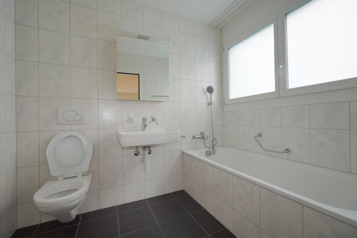 Helles Badezimmer mit Badewanne, Wand-WC und Waschbecken