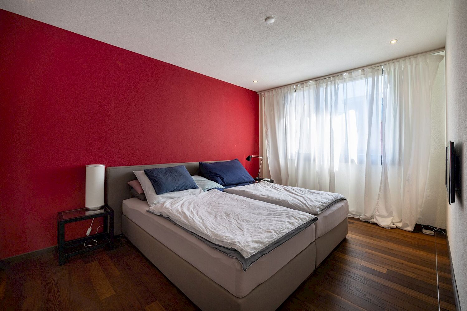 Modernes Schlafzimmer mit Doppelbett und roter Akzentwand