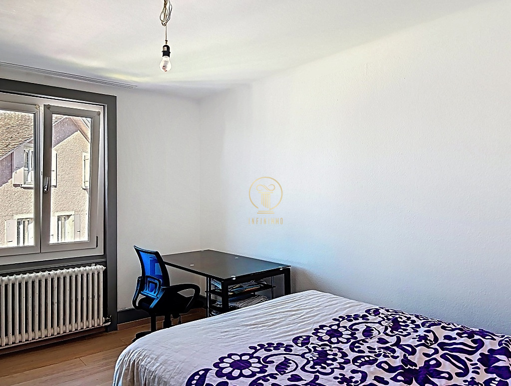 Schlichtes Schlafzimmer mit Fenster und Schreibtisch
