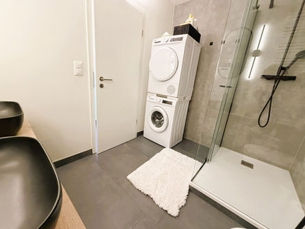 Badezimmer mit Dusche und Waschmaschinenstapel