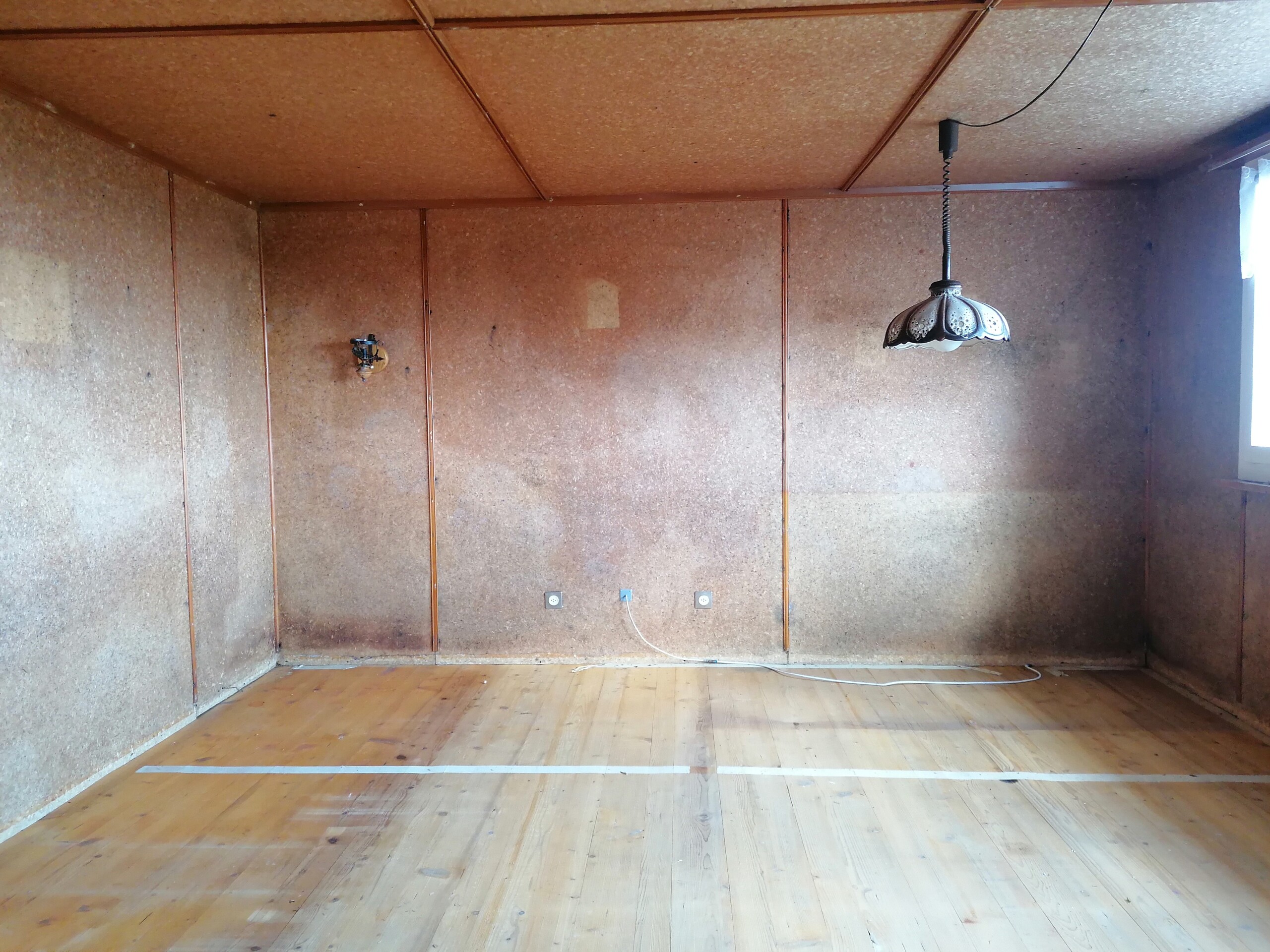Leerer, holzverkleideter Raum mit Fenster