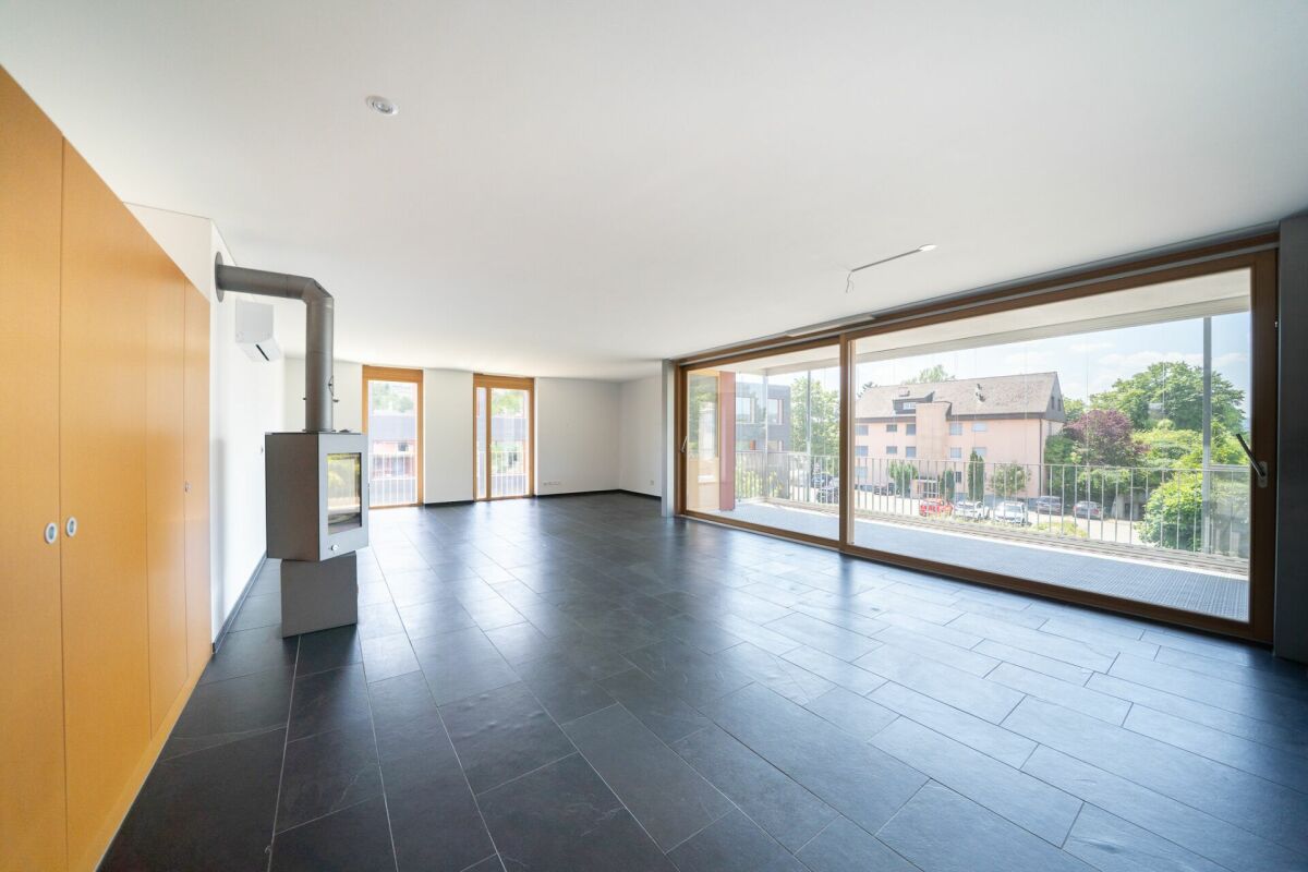 Großer Wohnraum mit Kaminofen und Balkonblick