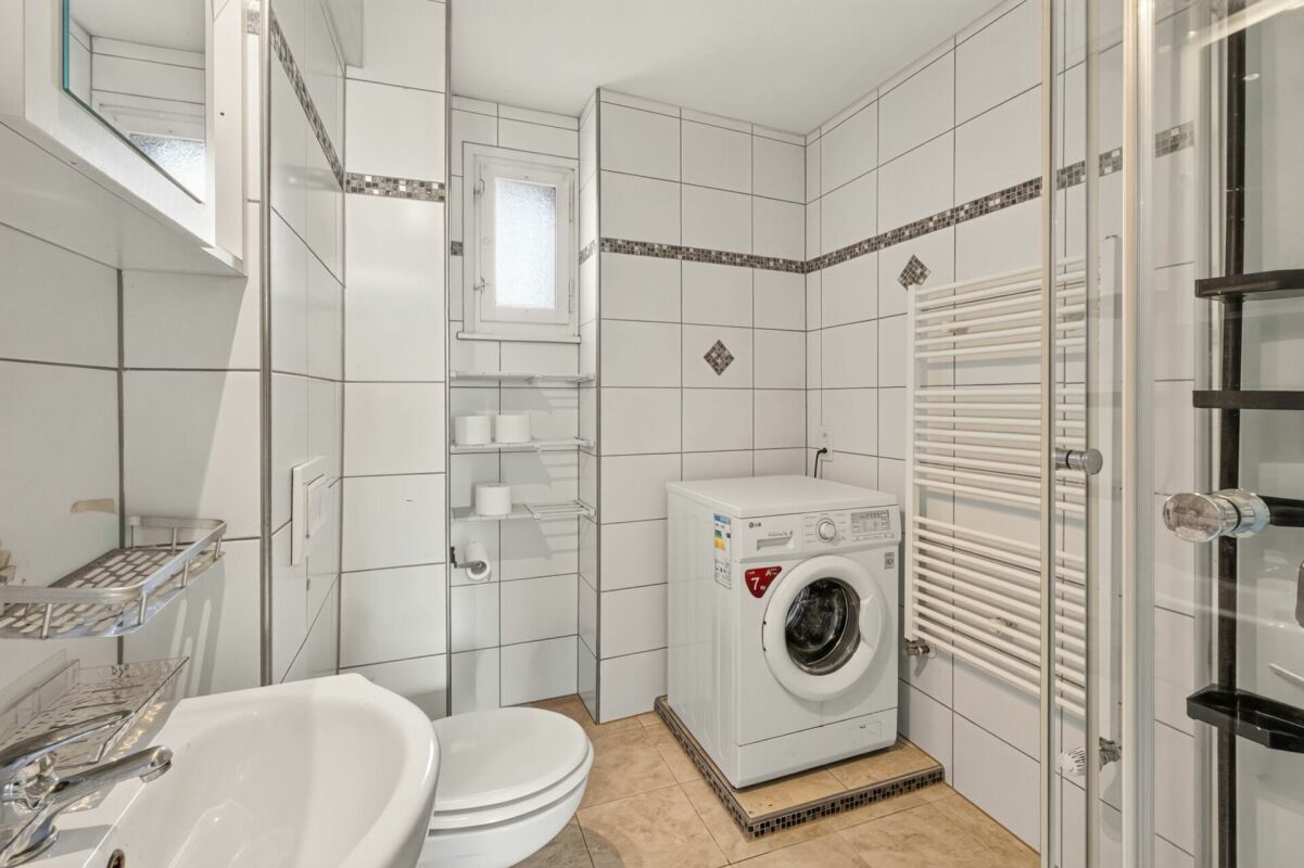 Helles Badezimmer mit Waschtisch, WC, Dusche und Waschmaschine