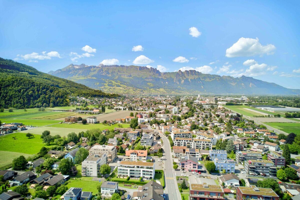 Luftaufnahme einer Stadt im Tal vor einer Gebirgskette