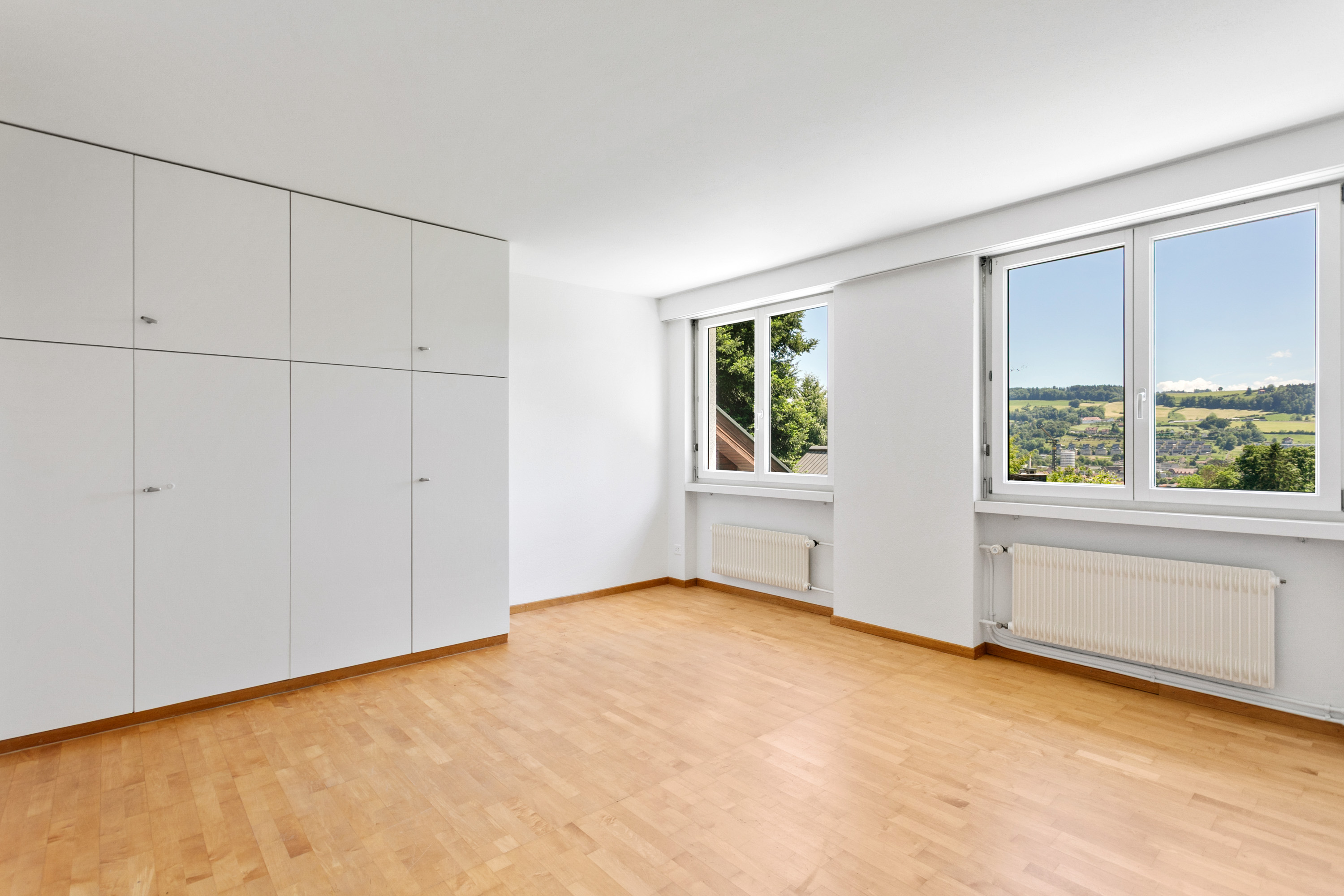 Helles, leeres Zimmer mit Einbauschrank und Bergblick