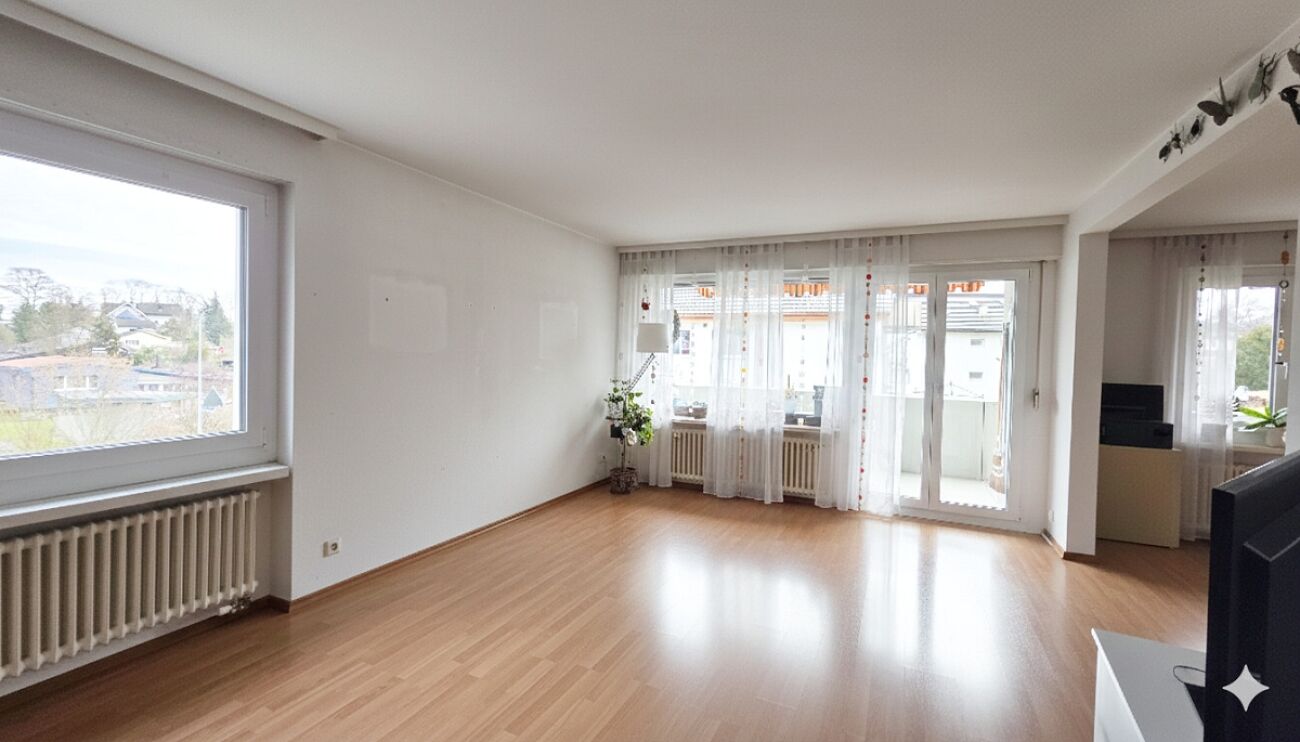 Heller Wohnraum mit Balkon und großen Fenstern