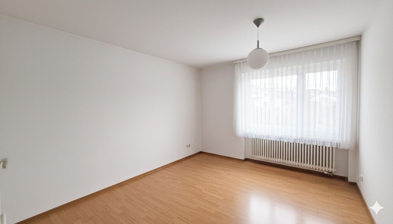 Heller, leerer Wohnraum mit Fenster und Heizkörper